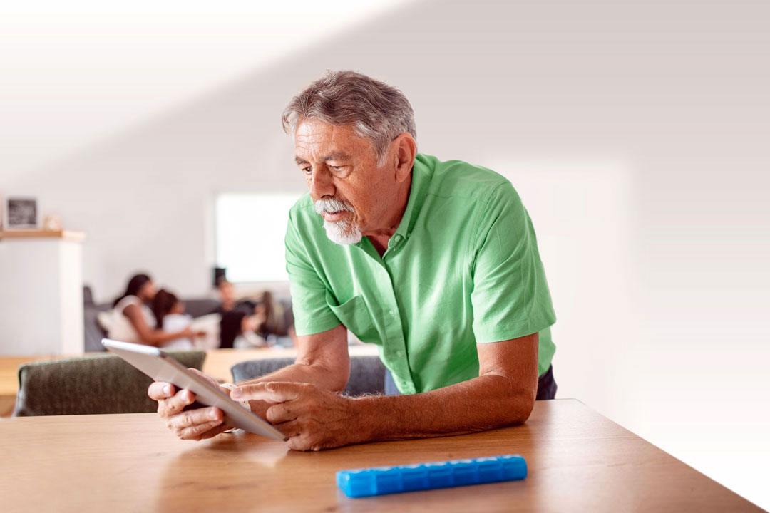 Diverse senior man on tablet looking up accepted health plans with Optum.