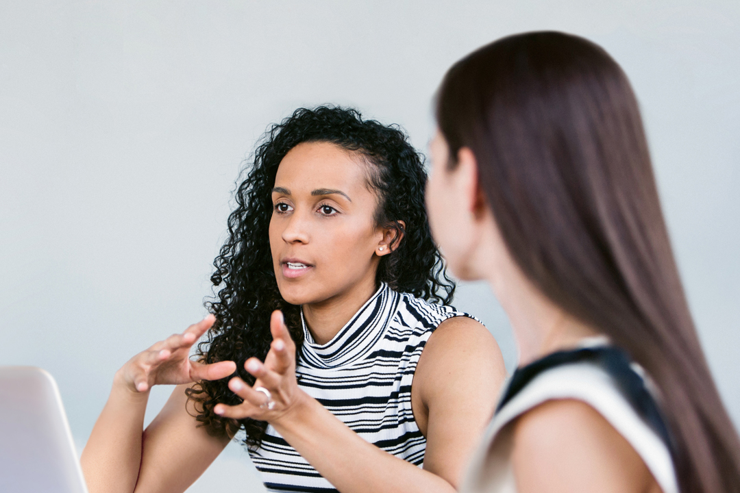 two women talking over laptop