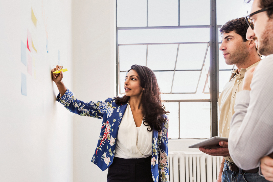 woman presenting to team on a whiteboard