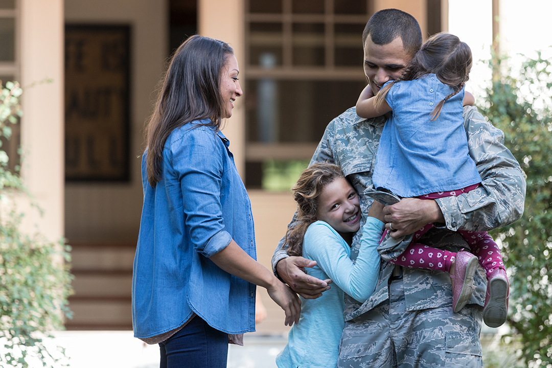 Military man embracing his family