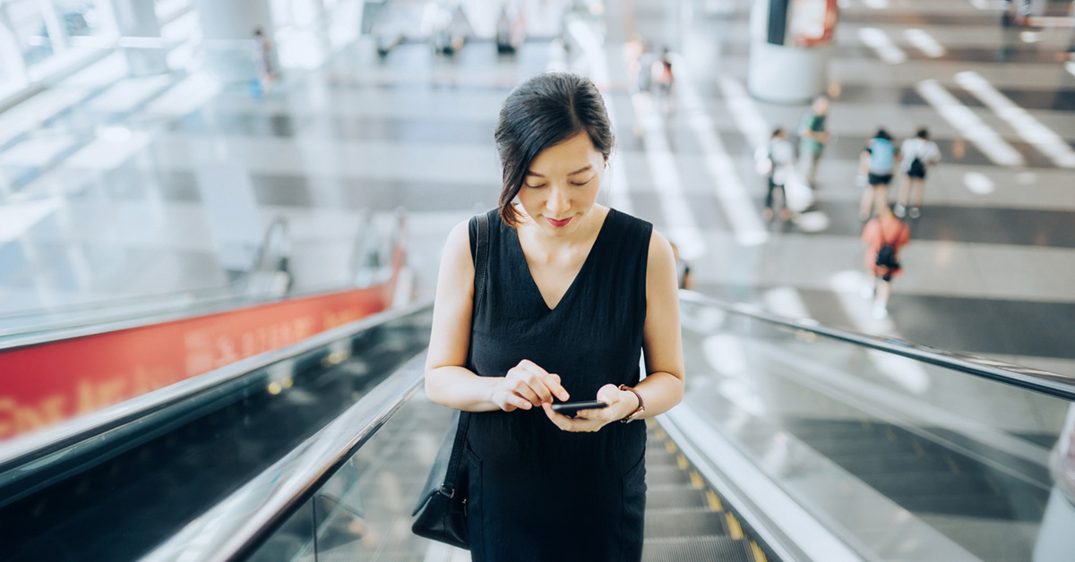 lady looking at phone on escalator