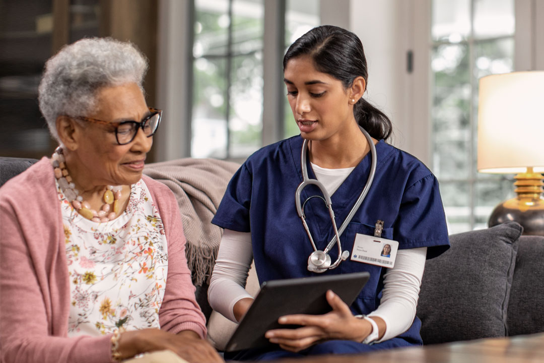 Female patient and provider looking at a tablet in patient's home