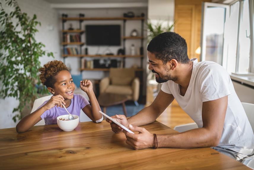 Father and daughter who lives with diabetes eating cereal at table