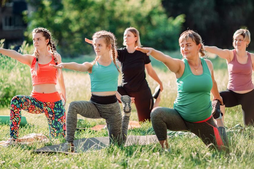 A group of women doing yoga outside in a field