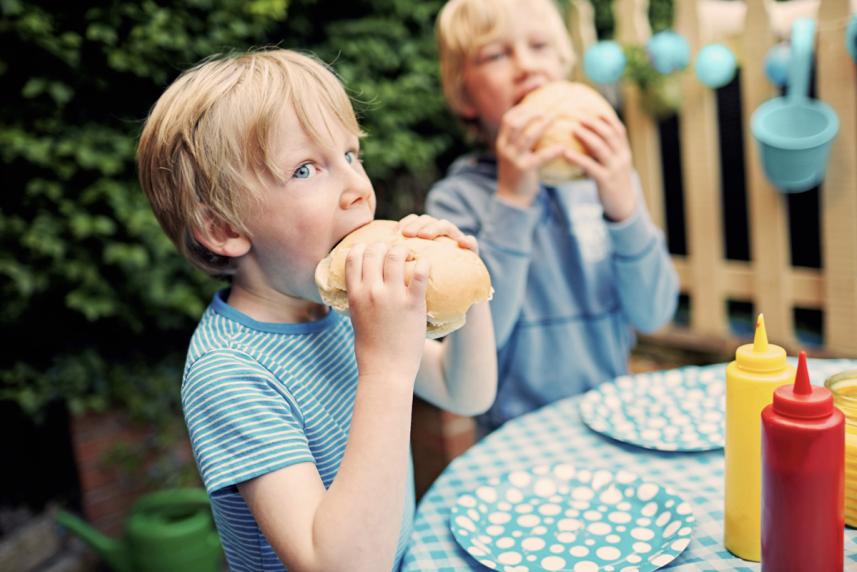 Kids sitting at picnic table eating burgers for a story on healthy barbecues