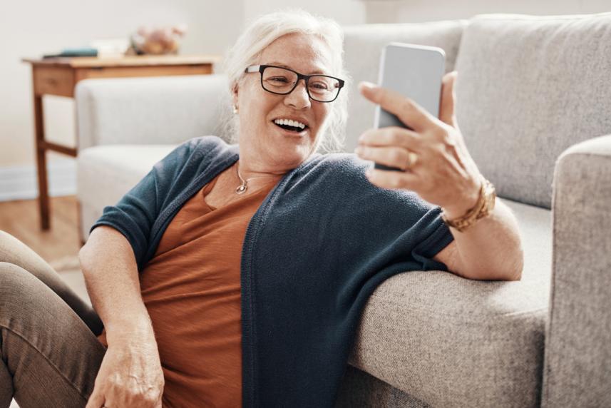 An older woman smiling at something on her phone