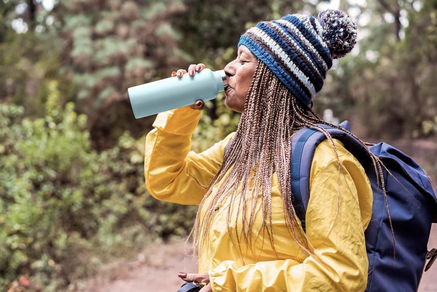 Woman drinking water while hiking for an article on healthy kidneys