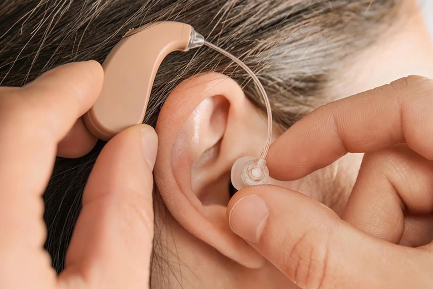 Older woman putting in a hearing aid