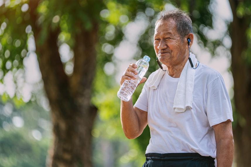 An older man drinking water after exercising outside