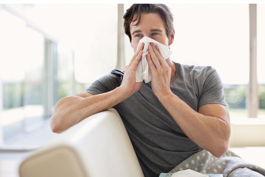 Man blowing his nose for an article about colds, flu, allergies and COVID