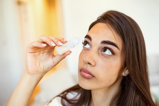 Woman using eye drops for an article on healthy vision