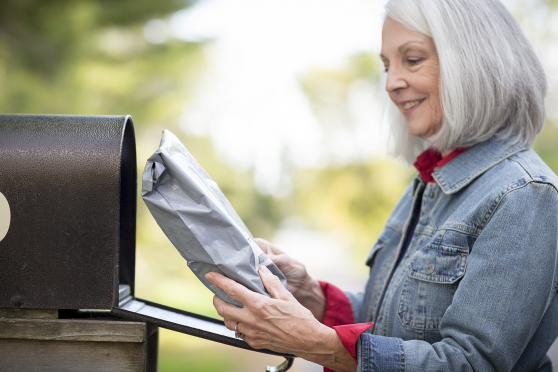 Older woman taking package out of mailbox