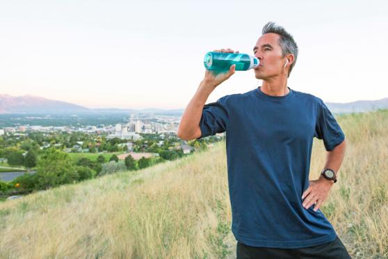 A man drinking water while hiking on a hilltop