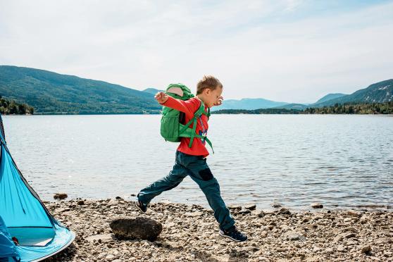 A child skipping along a lakeside shore
