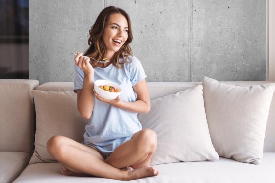 Woman eating from a bowl of fruit for an article about a low FODMAP diet