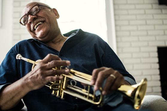 Senior man laughing while holding a trumpet
