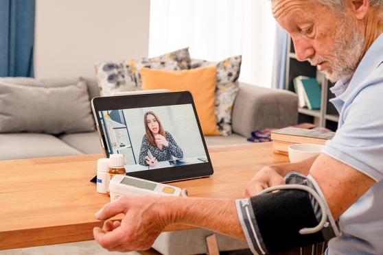 Senior man taking his blood pressure at home with virtual nurse
