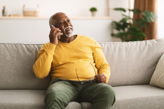 Senior man talking on the phone at home on the couch