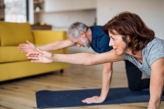 A senior couple at home doing yoga on the floor for bladder health
