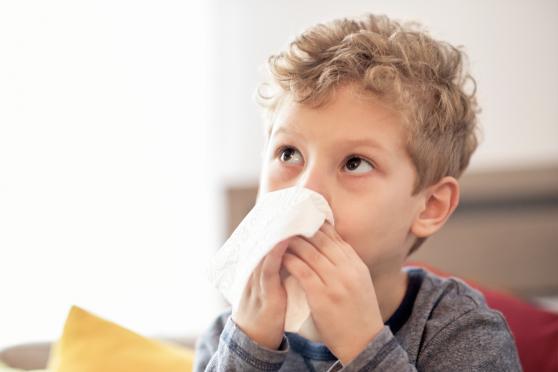 Young boy wiping his nose with a tissue for an article on allergies