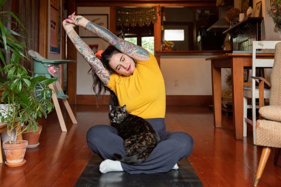 Woman stretching on floor with cat on lap
