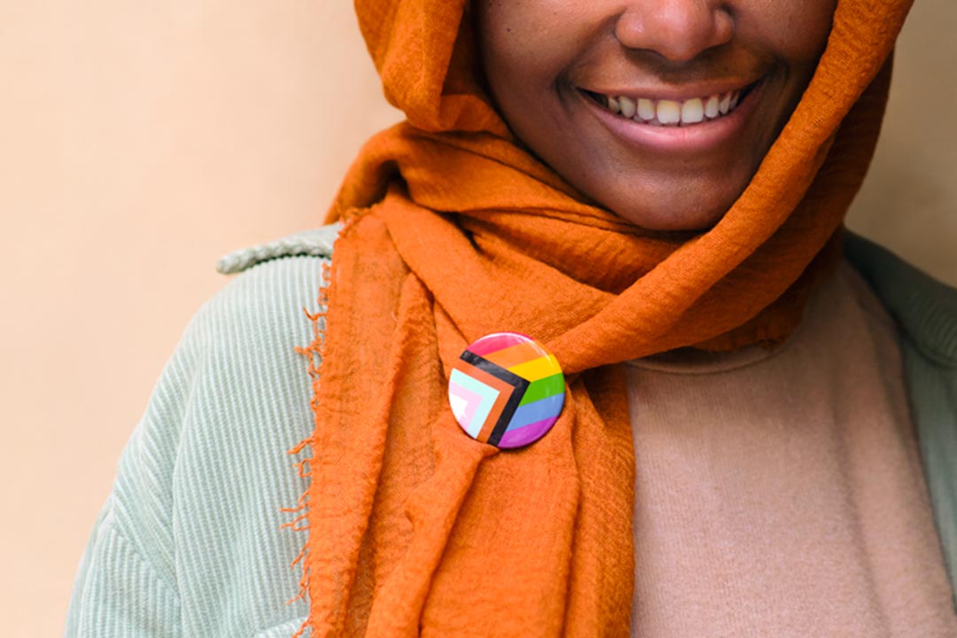 Woman wearing headscarf with a 'Progress' Pride Flag button by Daniel Quasar